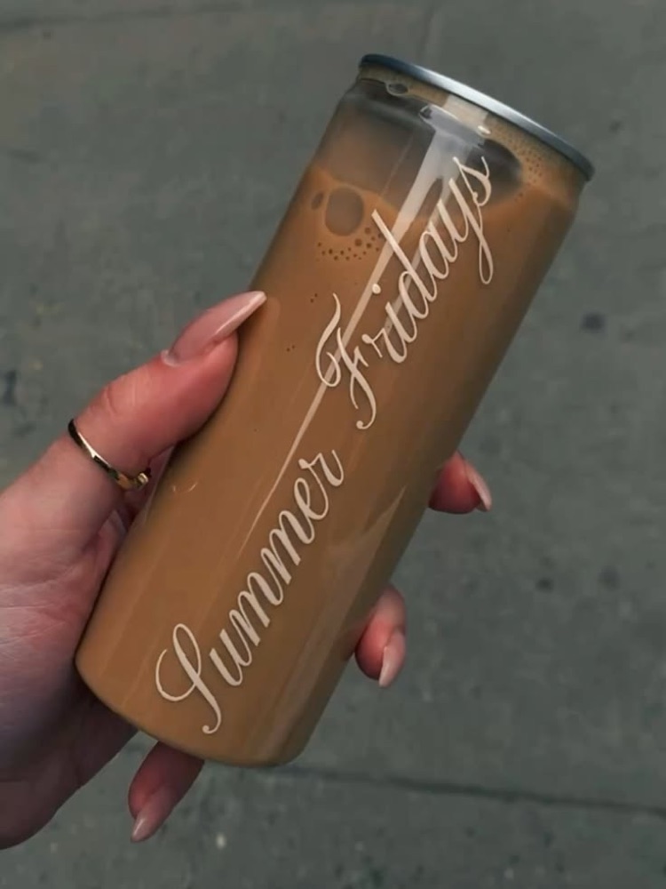 A branded iced coffee can held up on the street